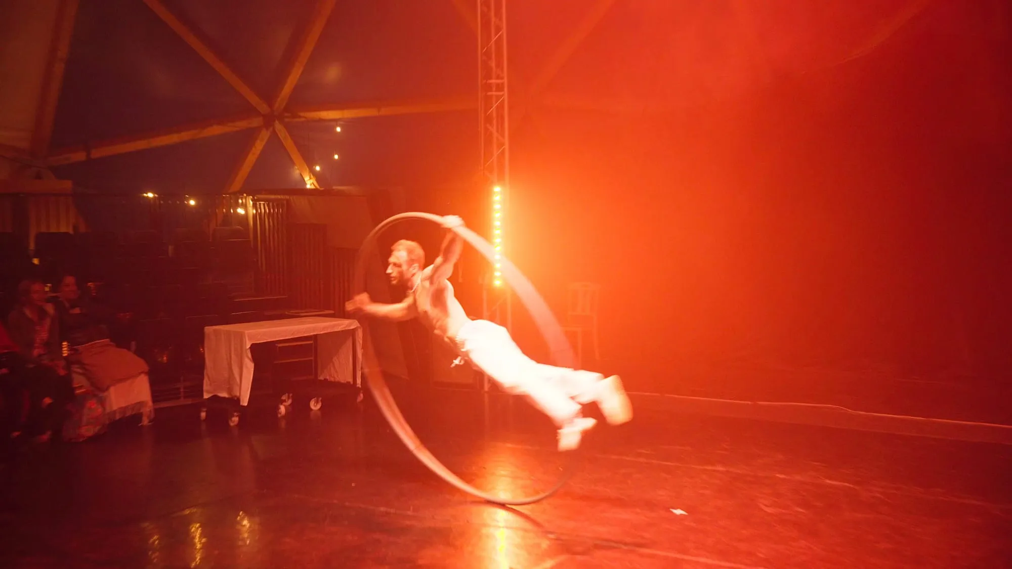 Schräg im rollenden Cyr Wheel, ein Bein gestreckt, auf der Bühne des Pepe Dome vor Publikum
